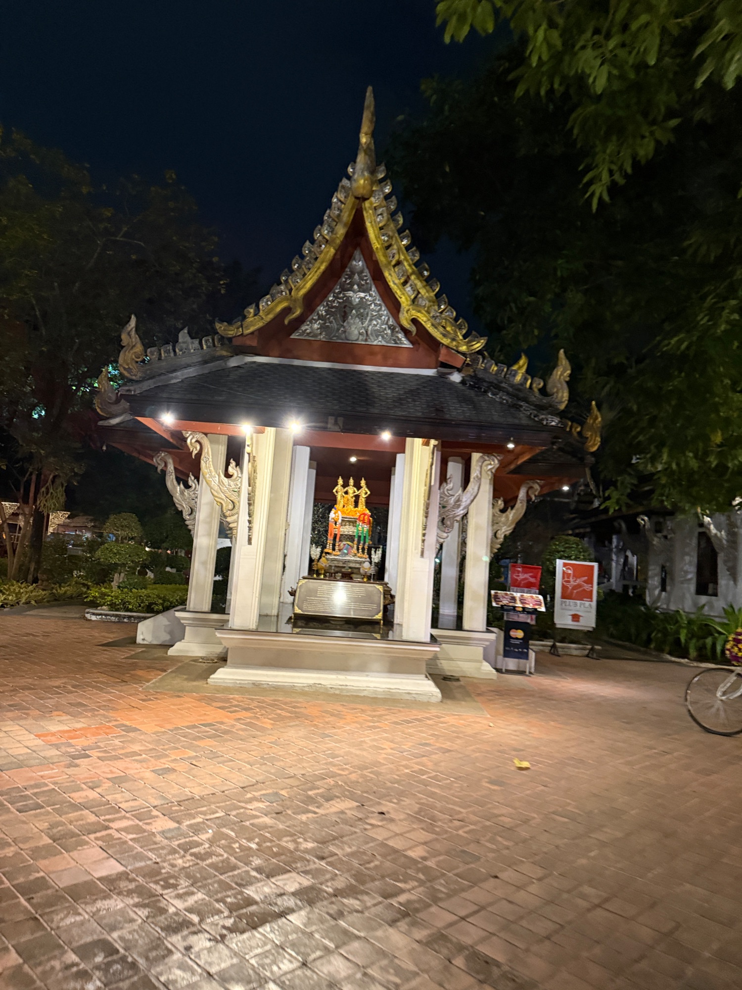Ornate Thai temple with golden pointed spire and red decorative elements illuminated at night