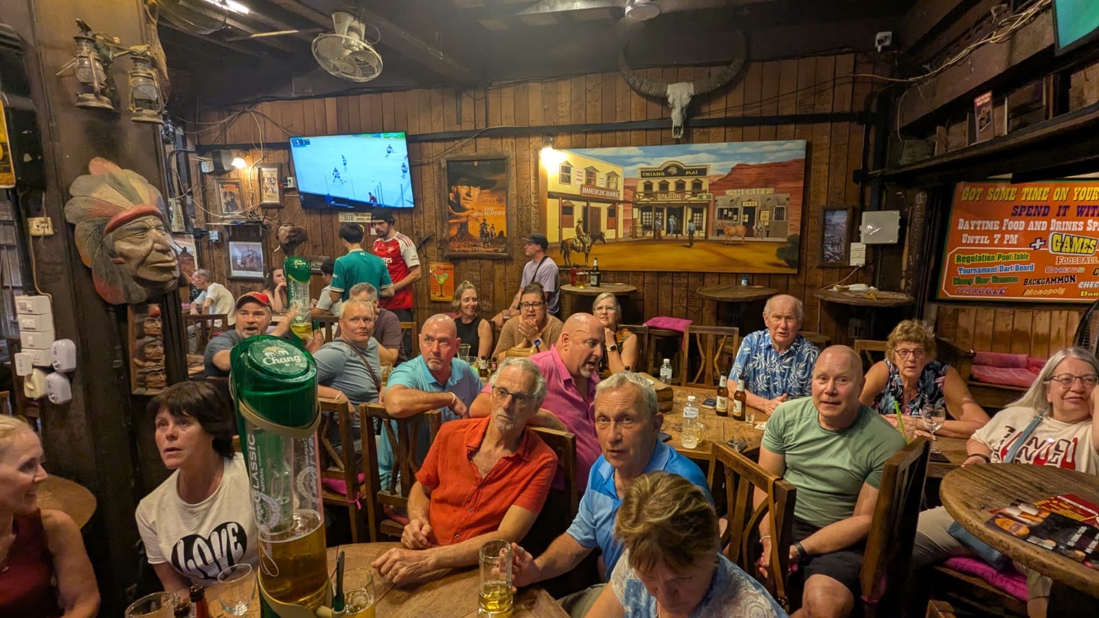 Interior of a rustic wooden bar with mounted animal heads, vintage decor, and patrons seated throughout