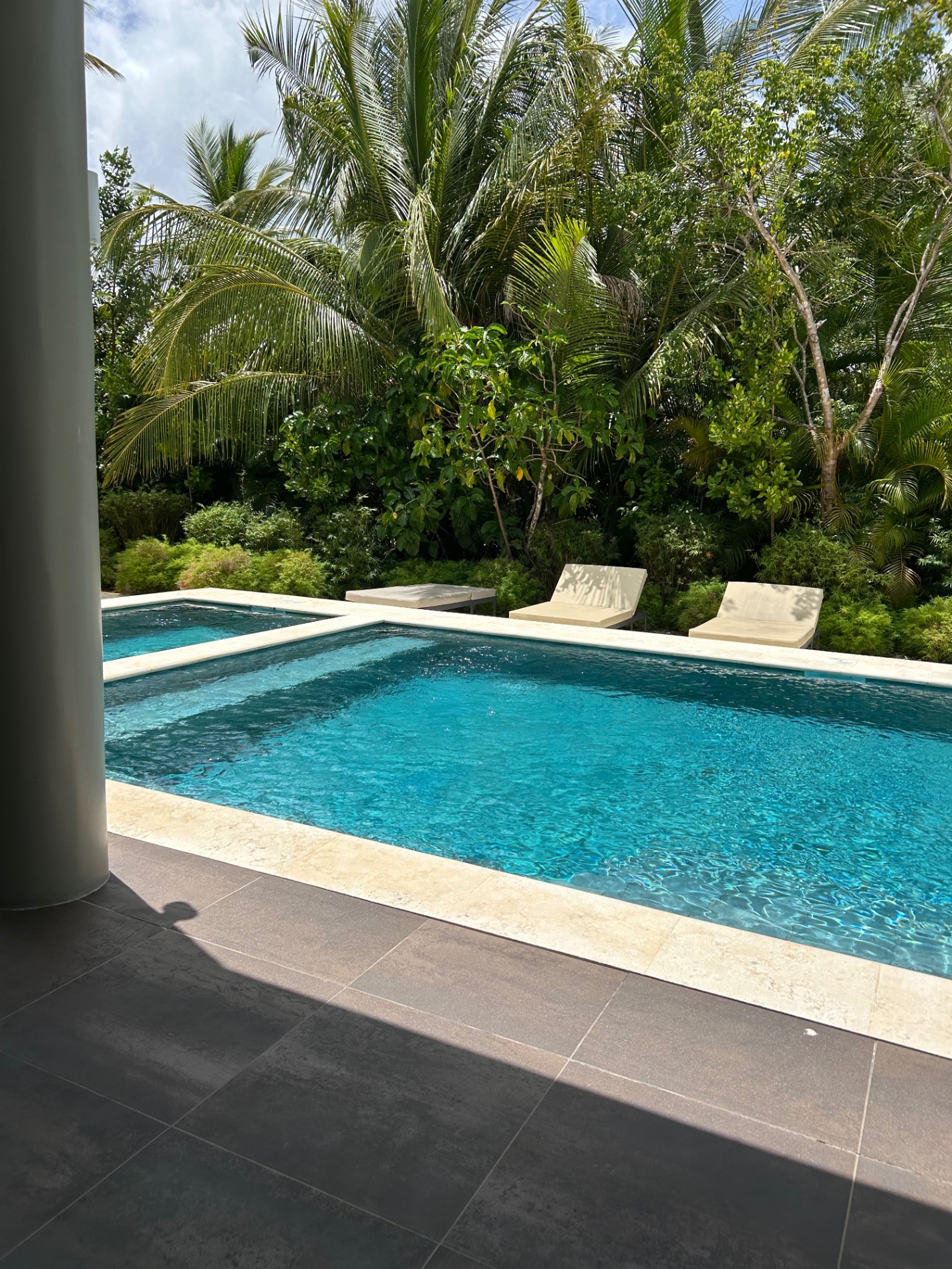 Two pools surrounded by lush tropical vegetation and palm trees at resort