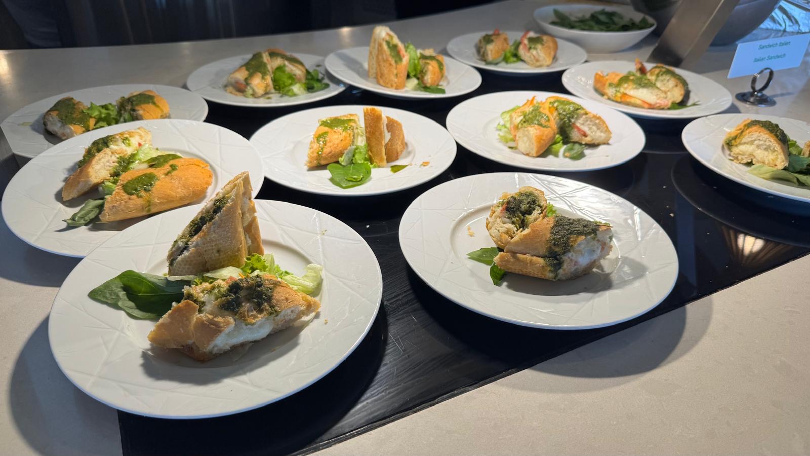 Multiple plates of grilled fish with green herb garnish arranged on black surface