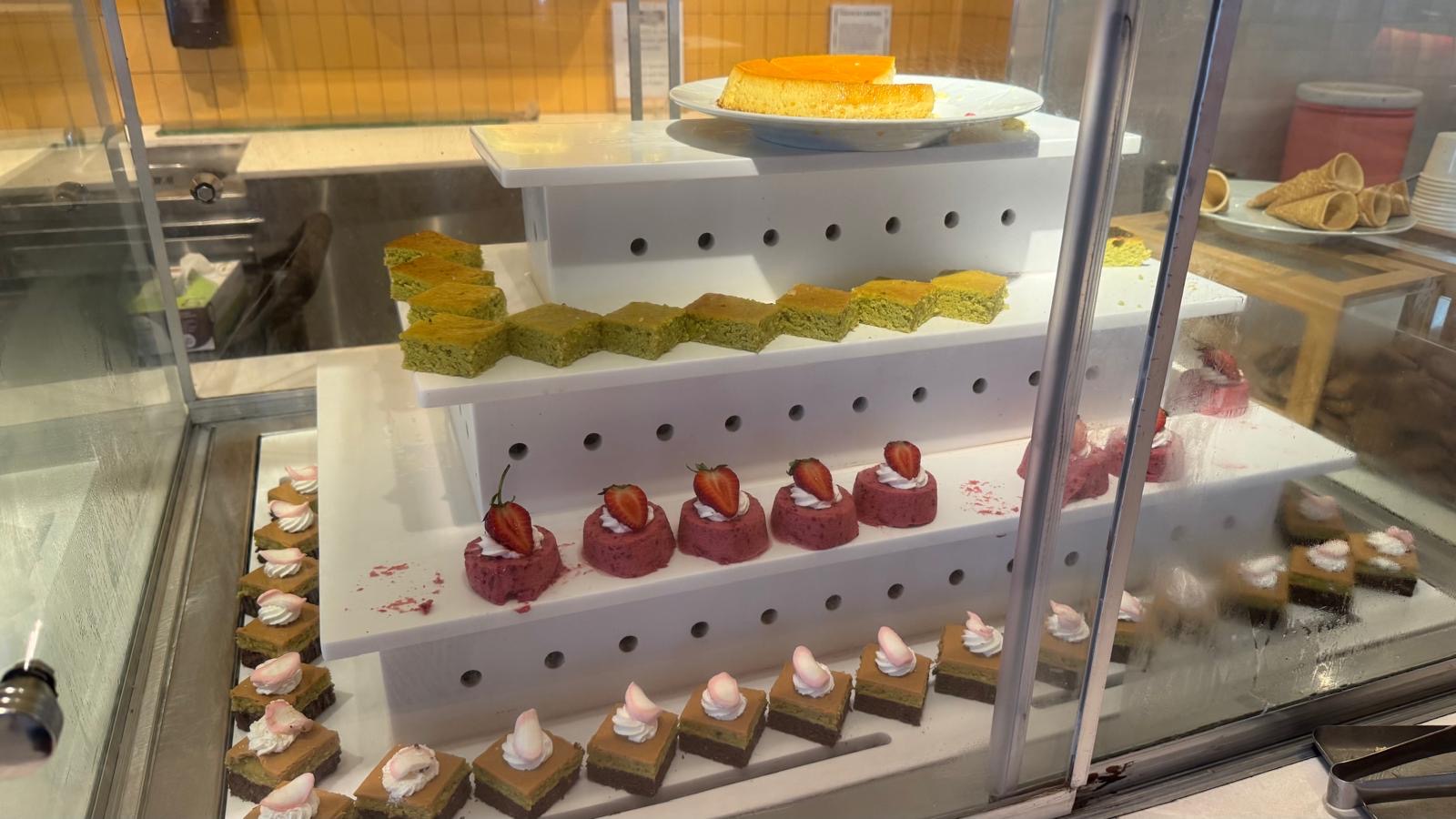 Tiered glass display case with pastries, cakes, and desserts in a resort bakery