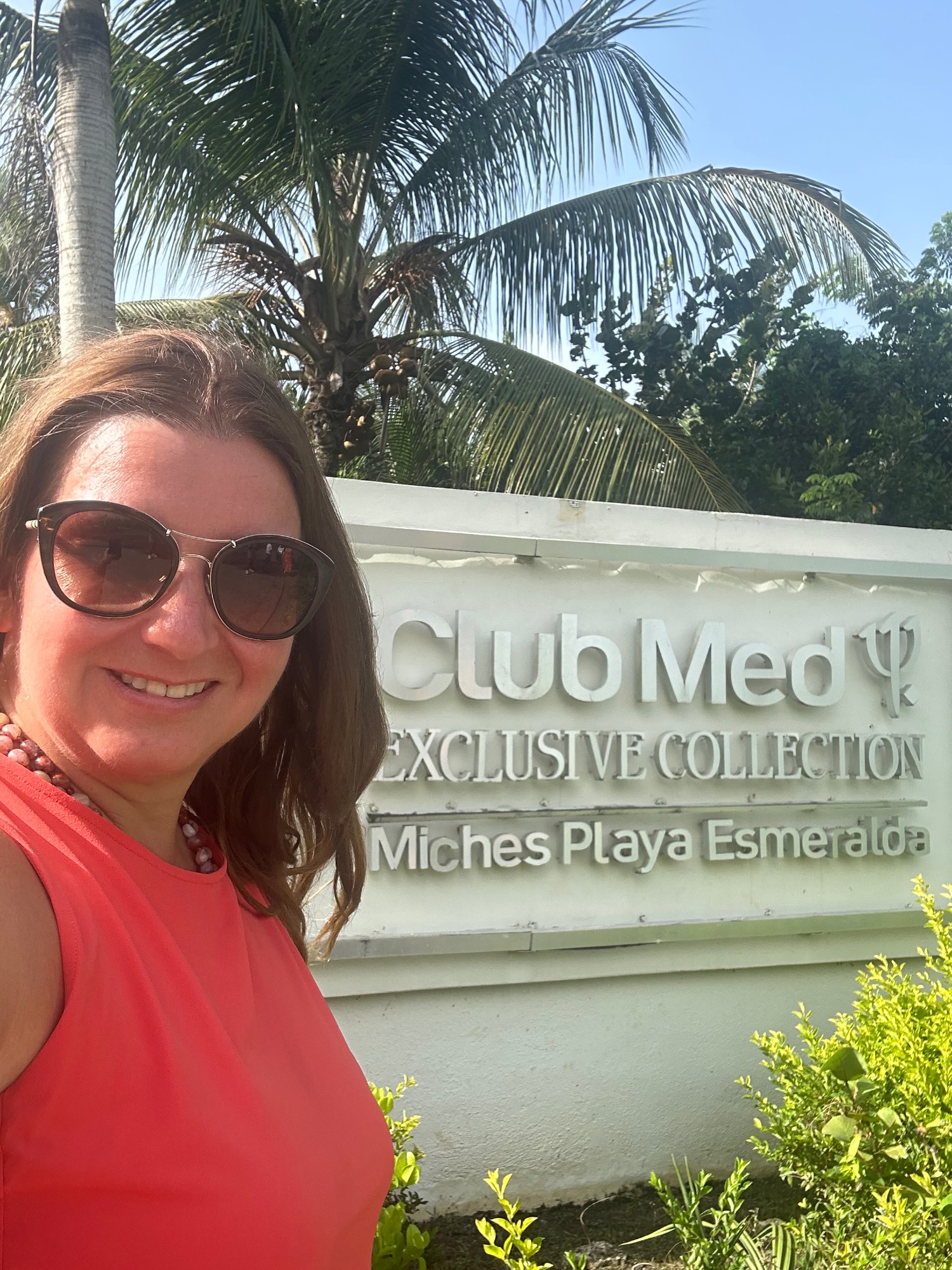Woman in red tank top smiling at Club Med Exclusive Collection Miches Playa Esmeralda sign