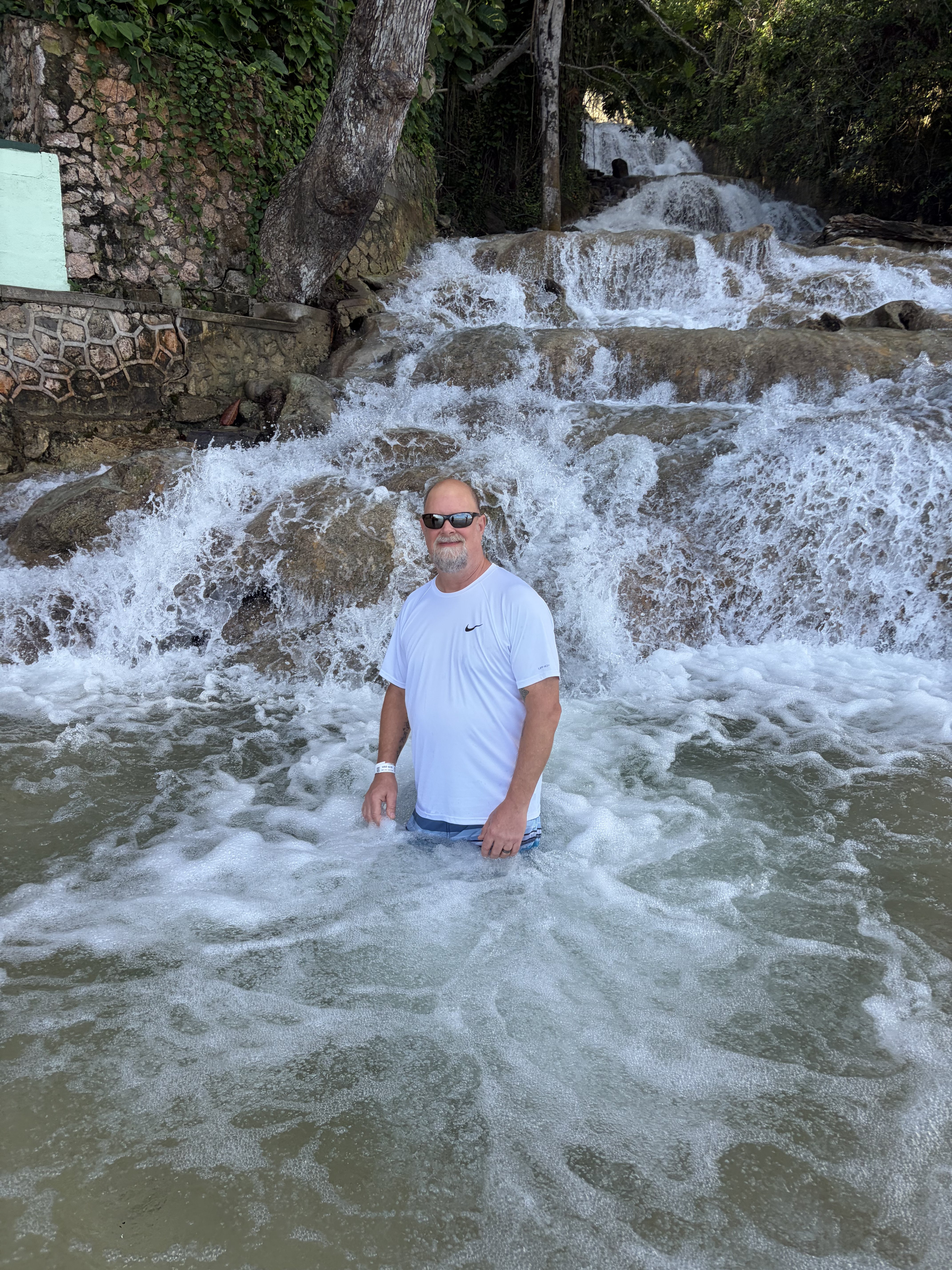 Man wading in cascading white water at Dunn's River Falls with limestone terraces