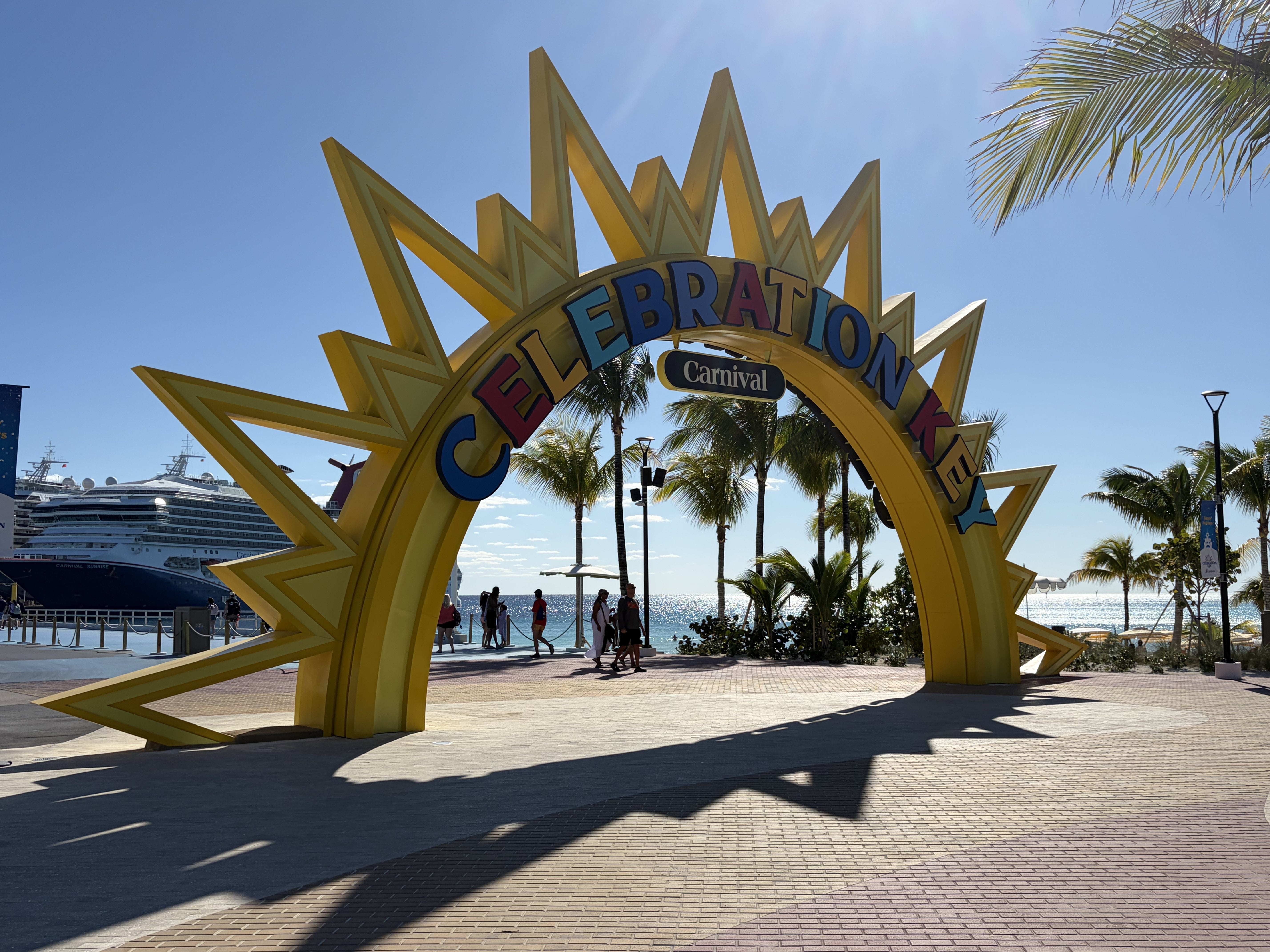 Carnival Celebration arch entrance at a cruise port with palm trees and ships visible