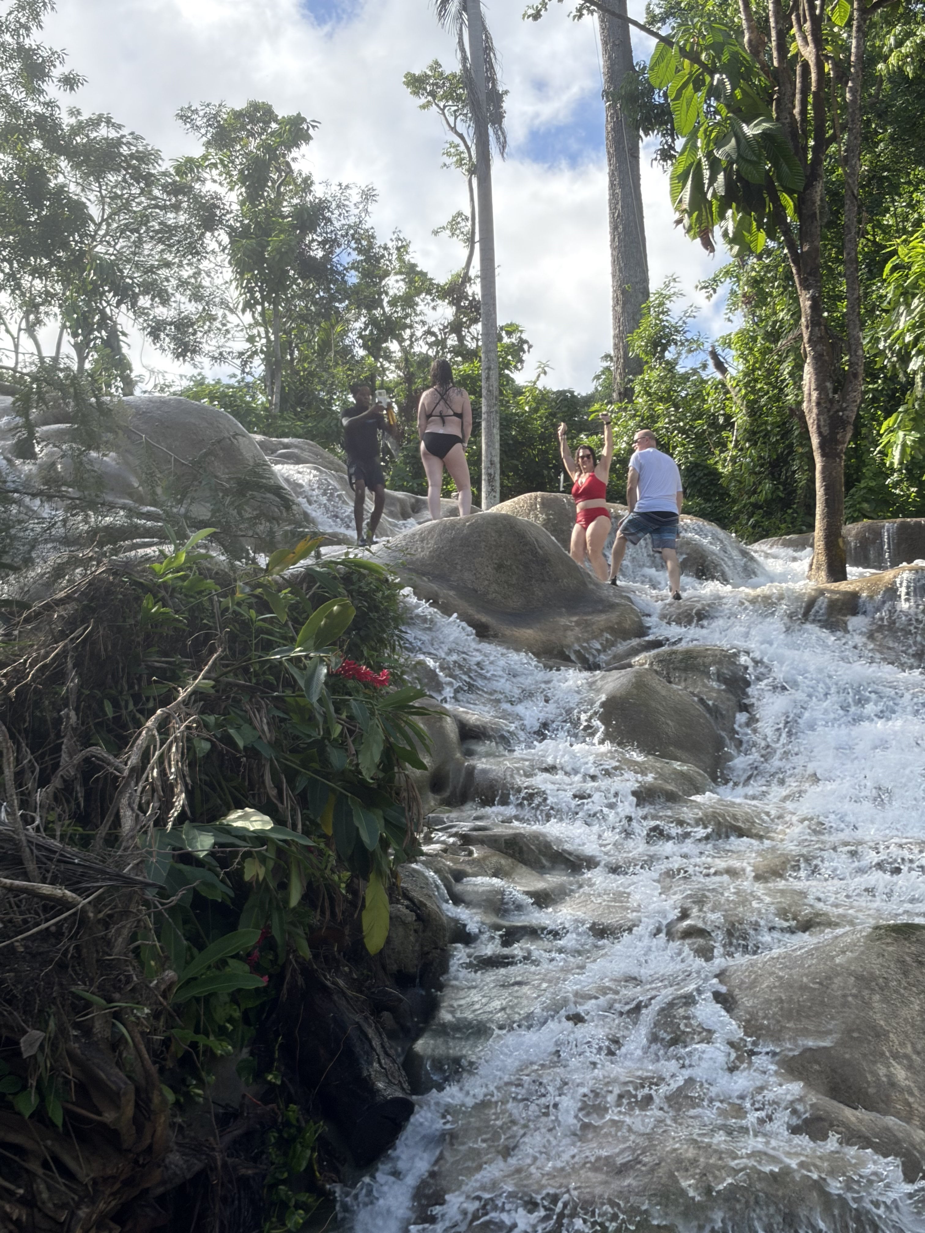 Woman in red bikini posing at Dunn's River Falls with cascading white water and rocks