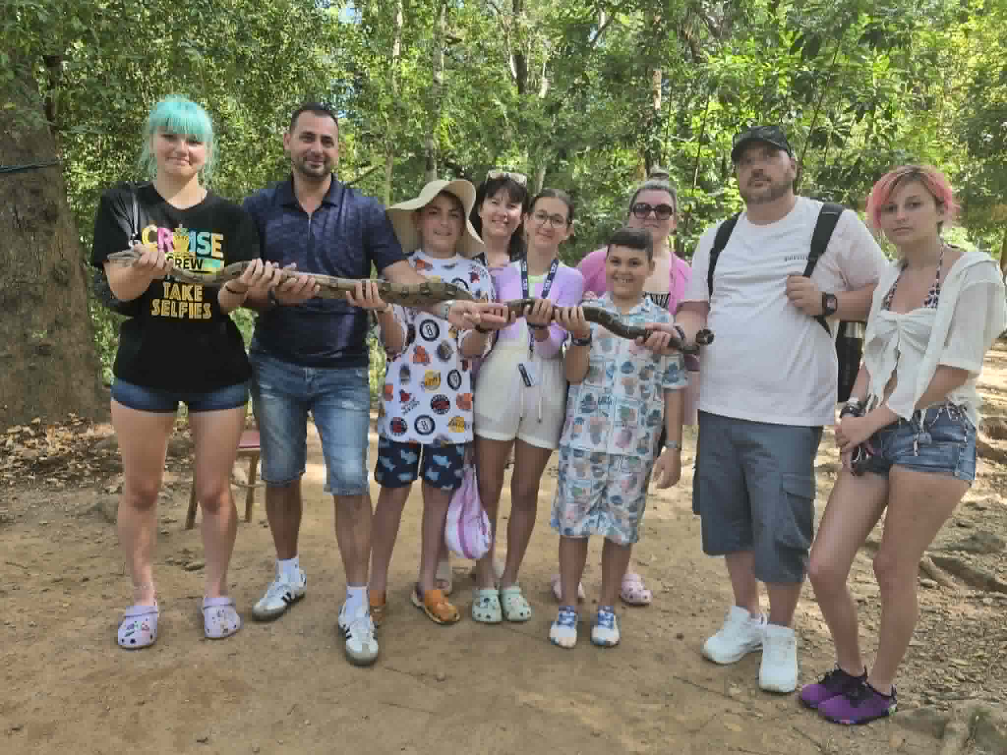 Group of nine people holding a large stick together on a forest path during a Western Caribbean excursion